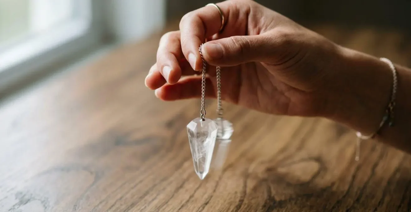 Main tenant un pendule en cristal lors d'une séance de calibration pour établir la convention mentale