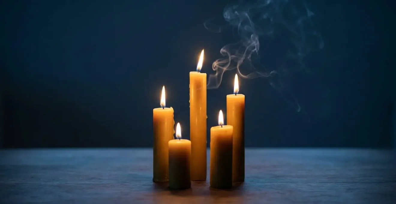 Composition minimaliste de bougies allumées créant une atmosphère méditative avec jeu d'ombres et lumières